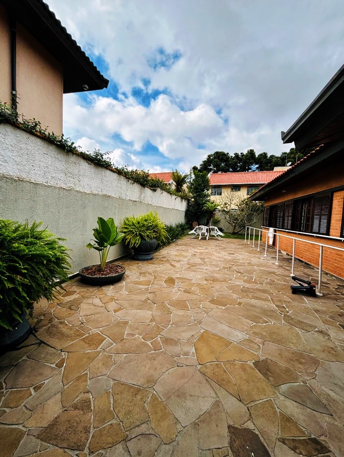 Área externa privativa com piso de pedra, plantas e mesa ao ar livre
