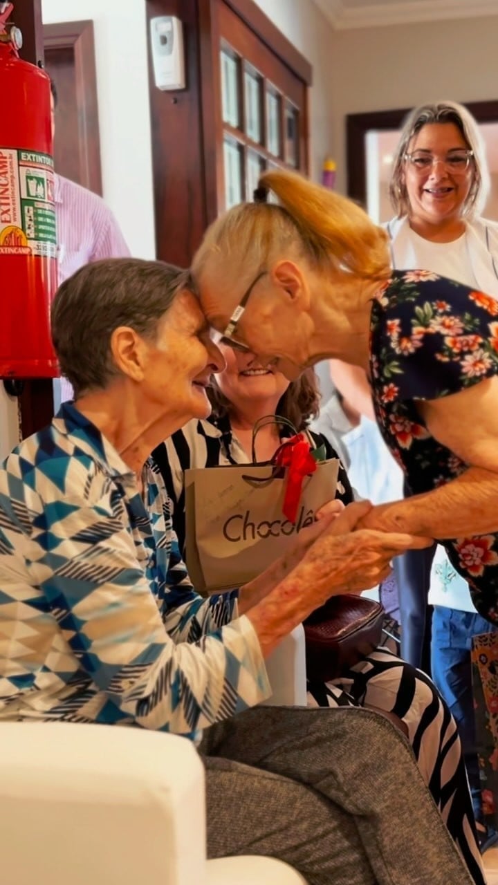 Duas residentes se cumprimentando com carinho durante uma comemoração